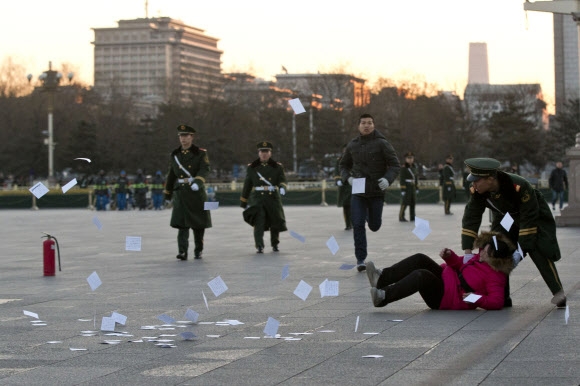 전국인민대표대회가 개막한 지난 5일 중국 베이징 중심부인 톈안먼 광장에서 한 여성이 인쇄물을 뿌리다 공안에게 제지당하고 있다. 베이징 AP 연합뉴스