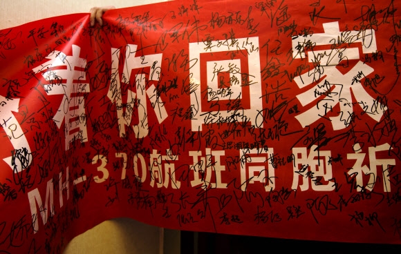 대학생들이 10일 중국 베이징의 한 대학에서 내건 현수막에 “MH370편의 동포여, 우리는 당신의 귀환을 바란다”는 구호가 적혀 있다. 탑승자들의 친인척과 친구들을 격려하기 위해 직접 찾아간 이 대학 학생들이 현수막에 서명을 남겼다.  베이징 AP 연합뉴스