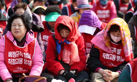 3일 서울 성북구 고려대학교에서 열린 청소·경비노동자 총파업 대회에 참가한 근로자들이 머플러로 햇빛을 피하고 있다.   연합뉴스