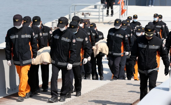 20일 오전 전남 진도군 팽목항에서 119 구조대원들이 세월호 침몰 사고로 숨진 희생자의 시신을 운구하고 있다. 연합뉴스