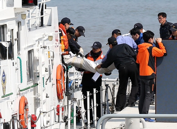 20일 오전 전남 진도군 팽목항에서 119 구조대원 및 해경 관계자들이 세월호 침몰 사고로 숨진 희생자 시신을 옮기고 있다.  연합뉴스