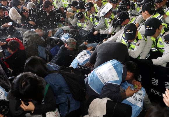 장애인의 날을 맞아 20일 오전 서울 강남고속버스터미널 경부선에서 고속버스 탑승을 시도하던 전국장애인차별철폐연대 회원들에게 경찰이 최루액을 쏘고 있다. 이들은 이날 부산·대구·세종시행 버스에 총 200좌석을 예매했다.  연합뉴스