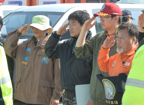21일 구조작업에 참여한 민간잠수부들이 전남 진도 팽목항에서 병원으로 옮겨지는 희생자 시신을 향해 거수경례를 하고 있다. 