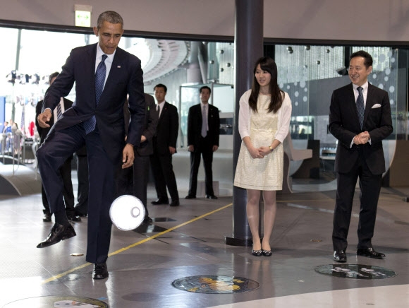 24일 도쿄의 과학박물관인 미라이칸을 방문한 오바마 대통령이 이동 성능을 개선한 로봇 아시모가 패스한 공을 차고 있다. 도쿄 AP 연합뉴스