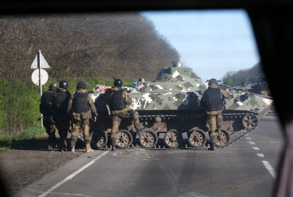 우크라이나 군인들이 24일(현지시간) 동남부 올렉산드리브카 지역의 한 도로를 탱크로 막고 있는 모습이 차창 밖으로 보이고 있다. 우크라이나 정부군은 이날 도네츠크주 슬라뱐스크 지역에서 친러시아 무장세력이 장악하고 있는 초소를 공격해 최대 5명의 무장대원을 사살했다. 올렉산드리브카 AP 연합뉴스