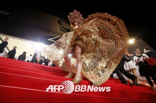 세계 스타들이 모두 모이는 제67회 칸 국제영화제에 정체 불명의 게스트가 화려한 금빛 의상을 입고 치마 부분을 들어올려 각선미를 보이고 있다.<br>ⓒ AFPBBNews=News1