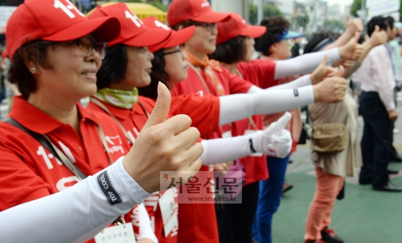 새누리당 선거운동원들이 25일 서울 광진구 건대입구역 주변에서 기호 1번을 의미하는 엄지손가락을 추켜세우며 지지를 호소하고 있다. 정연호 기자 tpgod@seoul.co.kr