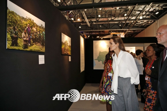 11일(현지시간) 영국 런던에서 열린‘분쟁지역 내 성폭력 근절을 위한 국제회의’에 유엔 특사로 참석, 사진 전시회를 둘러보는 안젤리나 졸리와 영국 외무장관 윌리엄 헤이그(오른쪽)