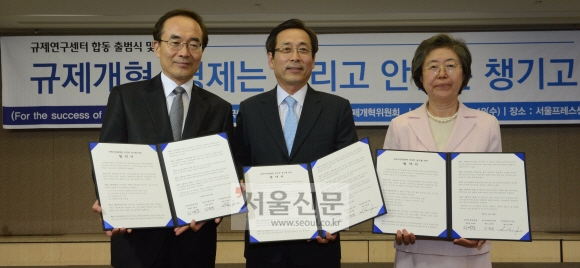 18일 서울 중구 한국프레스센터에서 열린 정부 규제연구센터 출범식의 참석자들이 규제비용을 분석, 검증하고 규제 제도와 정책을 연구하는 협약안을 들어 보이고 있다. 왼쪽부터 김태준 규제개혁위원회 공동위원장, 김준경 한국개발연구원(KDI) 원장, 이은재 한국행정연구원 원장. 안주영 기자 jya@seoul.co.kr