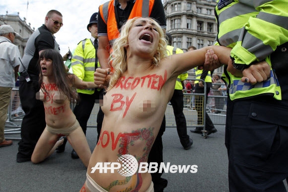 7일(현지시간) 영국 런던 중심부 국회의사당 앞 광장에서 우크라이나 여성 인권단체 피멘(femen) 회원들이 상의를 탈의한 채 여성할례(FGM)를 반대하는 반누드시위를 벌이던 도중 런던 경찰들에게 끌려가고 있다. ⓒ AFPBBNews=News1