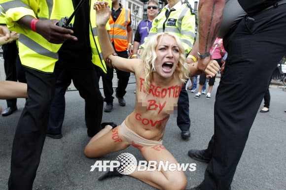 7일(현지시간) 영국 런던 중심부 국회의사당 앞 광장에서 우크라이나 여성 인권단체 피멘(femen) 회원들이 상의를 탈의한 채 여성할례(FGM)를 반대하는 반누드시위를 벌이던 중 경찰에게 끌려가고 있다. ⓒ AFPBBNews=News1