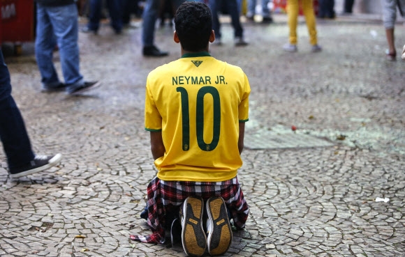 브라질 대표팀의 원톱 네이마르의 유니폼을 입은 축구팬이 9일 독일과의 준결승전에서 참패하자 ‘사죄’하는 듯 무릎을 끓고 있다.