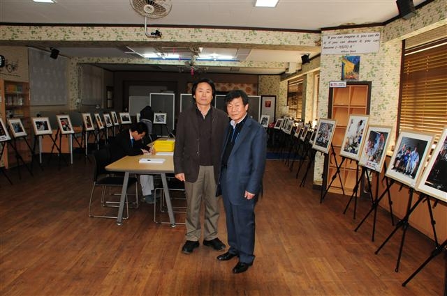 지난해 11월 18일 인천 제물포고등학교에 설치된 ‘사진으로 맛보는 대한민국 장터이야기’ 전시장에서 사진작가 이수길(왼쪽)씨와 이순통(오른쪽) 교장이 포즈를 취하고 있다. 이수길씨 제공