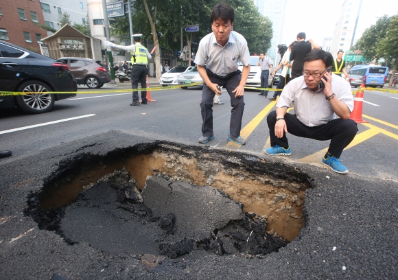 서울시 관계자들이 22일 오후 지하철 2호선 교대역에서 서초역 방면으로 약 100ｍ 떨어진 도로 한복판에 생긴 싱크홀을 들여다보며 사고 원인을 조사하고 있다.  연합뉴스