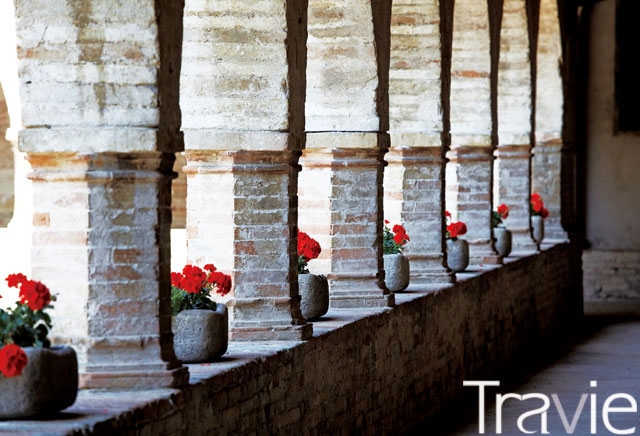 피아스트라 수도원의 회랑. 기둥 사이마다 붉은색 꽃이 놓여 있다.
