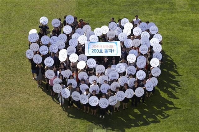 삼성화재 보험설계사 100명이 23일 서울시청 잔디광장에서 ‘500원의 희망선물’ 200호를 축하하기 위해 하트 모양으로 기념 촬영하고 있다. 삼성화재 제공