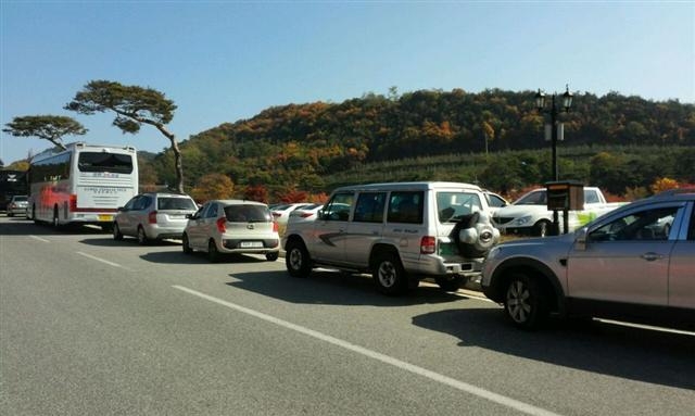 지난 25일 오전 경북 영주시 부석사 입구 영주시 공영주차장 요금소 내 주변 도로 양쪽에 대형 버스와 승용차 수십여대가 주차할 곳을 찾지 못해 도로를 무단 점거한 채 길게 줄지어 서 있다.