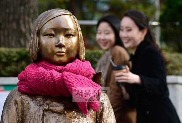 12일 서울 종로구 율곡로2길 일본대사관 앞에서 시민들이 목도리와 장갑을 한 소녀상을 바라보고 있다.  박지환 기자 popocar@seoul.co.kr