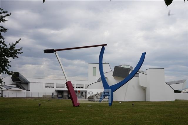 비트라 캠퍼스에 설치된 클라에스 올덴부리와 그의 아내 코샤 밴 브루겐의 대형 조각품 ‘균형 잡힌 연장들’(1984). 뒤로 보이는 건물이 프랑크 게리가 설계한 디자인 미술관이다.  