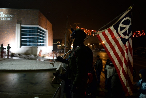 퍼거슨시 경찰서 앞 시위대는 각 주를 상징하는 별 대신 평화의 상징을 그려넣은 성조기를 들고 있다. 미주리주 AFP 연합뉴스