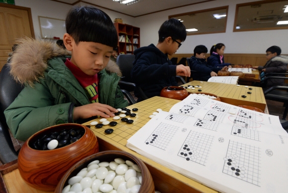 충암바둑도장에서 한 수련생이 바둑책을 보며 사활을 연구하고 있다.