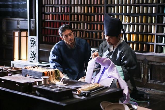 영화 속 조돌석(오른쪽)과 이공진은 세상에서 흔히 볼 수 있는 범재와 천재를 상징한다. 경쟁하고 갈등하는 관계이면서도 옷에 대한 열정이라는 공통분모를 갖고 서로 애정에 가까운 연민을 품는다. 상의원에서 조돌석이 수를 놓는 모습을 이공진이 지켜보고 있는 장면. 호호호픽쳐스 제공