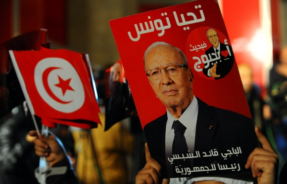 21일(현지시간) 치러진 튀니지 대선 결선투표 결과 세속주의 정치인 에셉시의 당선이 확정되자 지지자들이 수도 튀니스 거리로 나와 에셉시 사진을 들고 환호하고 있다. 튀니스 AP 연합뉴스