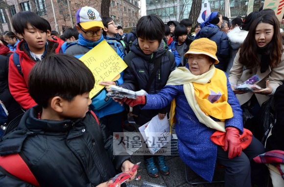 크리스마스 전날인 24일, 서울 종로구 일본대사관 앞에서 열린 1158번째 ‘수요집회’에 함께한 경기 부천동초등학교 6학년 학생들에게 위안부 피해자 이용수 할머니가 양말을 선물하고 있다. 이언탁 기자 utl@seoul.co.kr