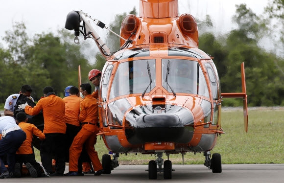 에어아시아 QZ8501기 실종 나흘째인 31일 인도네시아 팡칼란분에 착륙한 구조헬기에서 국가수색구조청 직원들이 사고 해역에서 수습해 온 시신 한 구를 내리고 있다. 팡칼란분 AP 연합뉴스