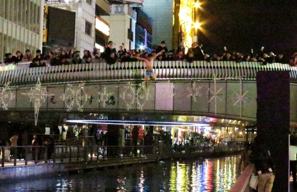 1일 오전 새해를 맞아 한 남성이 다리 위에서 일본 오사카(大阪)시 운하인 도톤보리가와(道頓堀川)로 뛰어들고 있다. 교도통신에 따르면 이날 0시께 일대에서는 남녀 60명가량이 새해를 기념하며 도톤보리가와에 뛰어들었다. 연합뉴스
