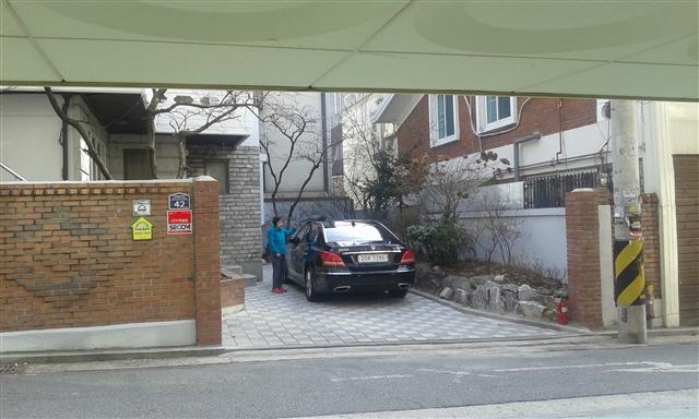 15일 신숙자씨가 용산구 한남동 자택에서 담을 허물어 조성한 주차장에 세운 차량을 닦고 있다.