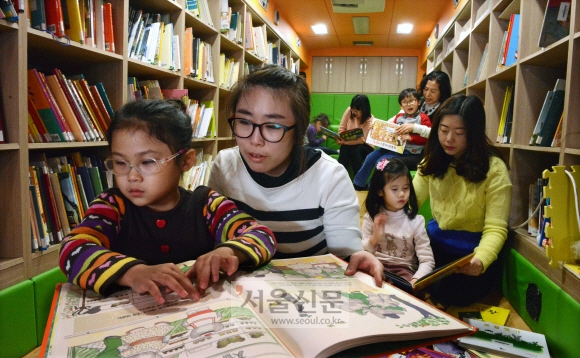 국립서울맹학교 어린이들과 교사들이 시각장애로 도서관을 이용하기 힘든 어린이들을 위해 한국점자도서관에서 운영하는 ‘북(book)소리버스’ 안에서 함께 촉각도서를 읽고 있다.