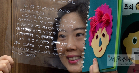 한국점자도서관에서 직원이 시각장애인을 위해 제작한 점자도서와 촉각도서를 들어 보이고 있다.
