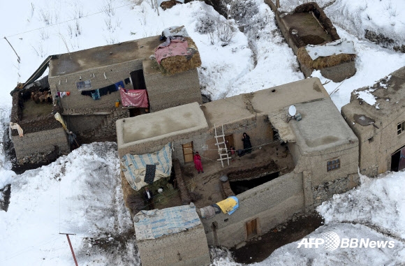 1일(현지시간) 아프가니스탄 북서부 판지시르 주의 한 마을에서 발생한 눈사태에서 살아남은 주민들이 구호물품을 운송하는 아프간 군 헬기를 올려다보고 있다.  ⓒAFPBBNews=News1