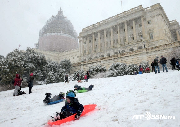 5일(현지시간) 미국 워싱턴 국회의사당의 서쪽 잔디밭에 눈이 쌓이자 어린이들이 언덕에서 썰매를 타고 있다. 국회의사당 잔디밭에서 썰매를 타는 것은 2001년 9·11테러 사건 이후 금지돼 왔었다. ⓒAFPBBNews=News1
