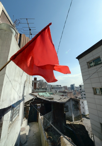 재개발을 반대하는 집에서 내건 빨간 깃발이 바람에 세차게 나부끼고 있다.