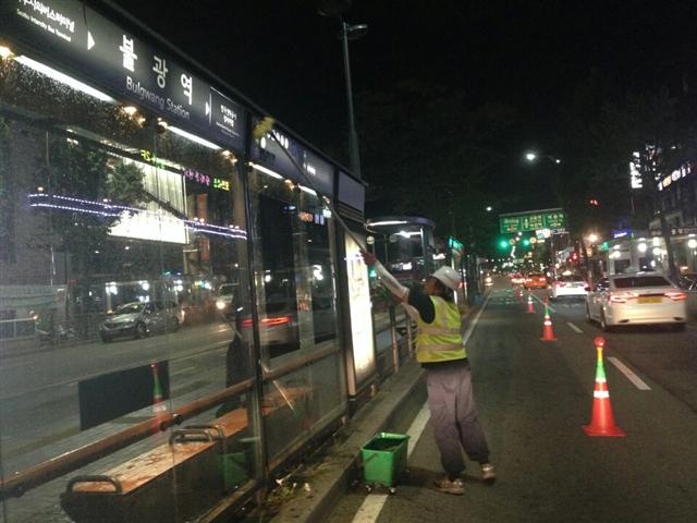 간접고용된 청소노동자 김영일씨가 차도에 서서 불광역 버스 정류장을 청소하고 있다. 안전콘이 설치돼 있지만 한밤중에 차량들이 쌩쌩 달려 김씨의 작업은 위험해 보인다. 김영일씨 제공