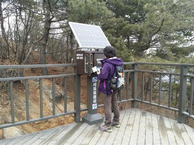 17일 한 등산객이 용마산 제2헬기장에 설치된 휴대전화 충전기를 사용하고 있다. 광진구 제공