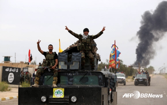 4월 1일(현지시간) 이라크 살라딘 주의 주도 티크리트에서 시아파 민병대원들이 치열한 교전 끝에 이슬람 국가(IS) 무장 세력을 격퇴한 후 탱크에 올라서서 양 손으로 V를 그리고 있다. ⓒAFPBBNews=News1