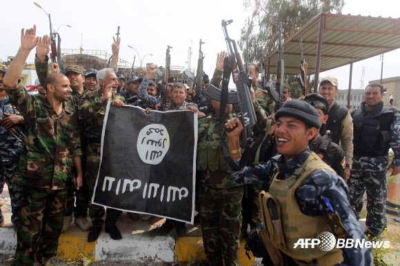 1일(현지시간) 이라크 살라딘 주의 주도 티크리트에서 시아파 민병대원들이 교정 중 빼앗은 이슬람 국가 깃발을 들고 포즈를 취하고 있다.  ⓒAFPBBNews=News1