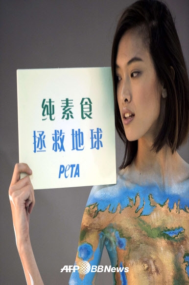 모델 켈리 친(Kelly Chin)’기후 변화와 싸워라. 채식으로 가자. Fight Climate Change:Go Vegan’라는 종이를 들고