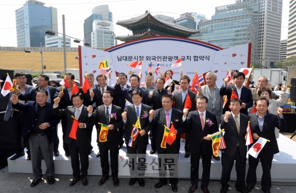 23일 오후 남대문시장 시계탑 광장에서 열린 남대문시장 외국인 관광객 유치를 위한 업무협약에 참석한 최창식 중구청장과 장재영 신세계백화점 대표, 김재용 남대문시장 상인회장 등이 만국기를 들고 파이팅을 외치고 있다. 도준석 기자 pado@seoul.co.kr