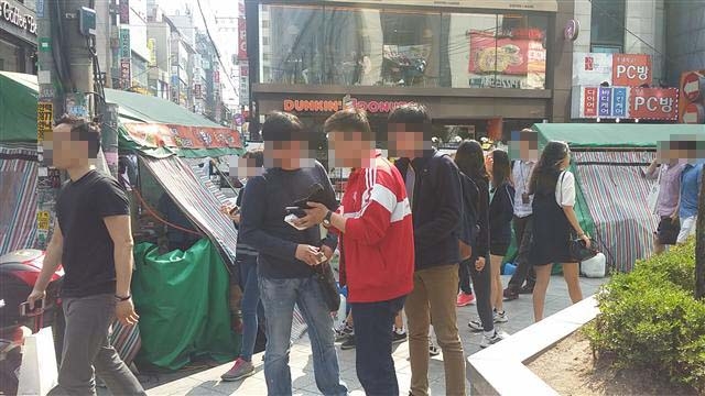 지난 1일 오후 서울 홍대입구역 9번 출구 계단을 오르는 외국인 여성의 치마 속을 동영상으로 찍다 걸린 20대 남성의 휴대전화를 지하철경찰대 경찰관 2명이 살펴보고 있다.