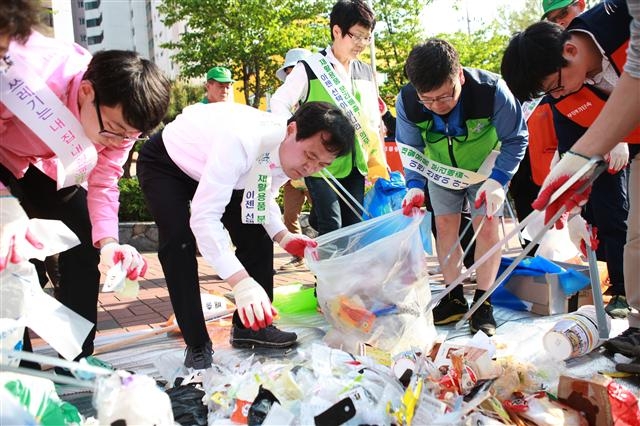 박겸수 강북구청장이 지난 1일 인수동 마을마당에서 구민에게 쓰레기줄이기에 대한 경각심을 심어 주기 위해 종량제 봉투에 섞여 버려진 재활용쓰레기를 분리하고 있다. 강북구 제공 