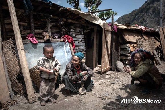 네팔 대지진 11일째인 6일 고르카 지역의 한 마을에서 지진 피해를 입은 두 여성이 아이를 바라보며 미소지고 있다. ⓒAFPBBNews=News1