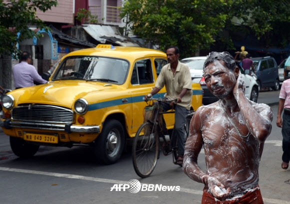 한 인도 남성이 10일(현지시간) 인도 콜카타의 길 한복판에서 도심에 설치된 상수도를 이용해 목욕을 하기위해 온몸에 비누칠을 하고 있다. ⓒ AFPBBNews=News1