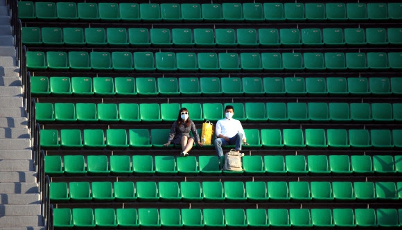 지난 12일 두산과 NC의 경기를 보기 위해 서울 잠실구장을 찾은 관중이 한적한 외야석에 마스크를 쓰고 앉아 경기를 관람하고 있다. 연합뉴스