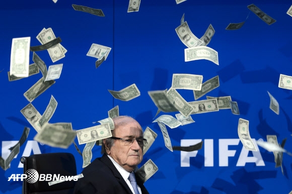 20일(현지시간) 스위스 취리히에서 열린 기자회견 도중 한 영국 코미디언이 던진 가짜 돈다발이 제프 블래터 국제축구연맹(FIFA) 회장 주위로 뿌려지고 있다.  국제축구연맹(FIFA)은 내년 2월26일 차기 회장선거를 연다고 밝혔다. ⓒ AFPBBNews=News1