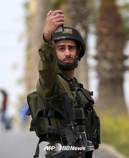 이스라엘군은 우리 돈으로 31만원가량의 월급을 받습니다. 그런데 예비군 훈련비가 하루 10만원이라고 합니다. 휴대전화로 사진을 촬영하는 이스라엘 병사.   AFPBBNews=News1