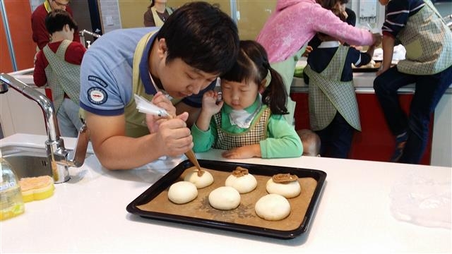 성동구 건강가정지원센터에서 진행한 ‘부자의 취향’ 요리 프로그램에 참여한 부녀가 다정하게 빵을 만들고 있다. 